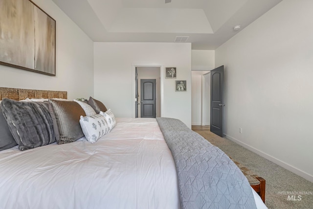 carpeted bedroom with a tray ceiling