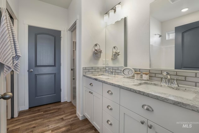 bathroom with backsplash, a shower, hardwood / wood-style floors, and vanity