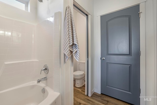 bathroom with wood-type flooring, shower / bath combination, and toilet