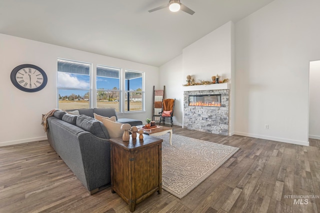 living room with hardwood / wood-style floors, ceiling fan, a stone fireplace, and high vaulted ceiling