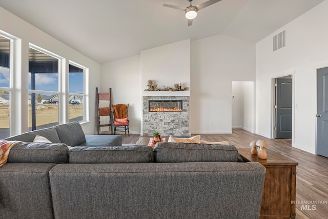 living room with ceiling fan, wood-type flooring, a fireplace, and vaulted ceiling