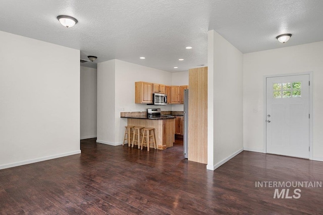 316 N 11th St, Payette, ID 83661 - kitchen with stainless steel appliances, dark countertops, a breakfast bar, wood finished floors, and a textured ceiling