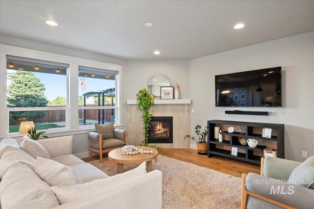 living room featuring a tile fireplace, wood finished floors, and recessed lighting