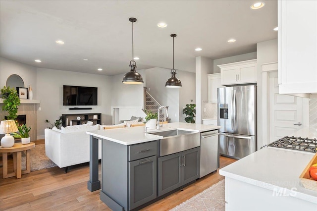 kitchen with gray cabinetry, stainless steel appliances, a fireplace, a sink, and white cabinetry