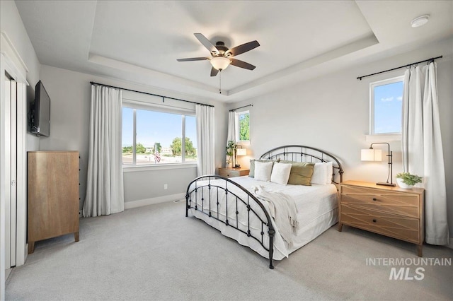 bedroom featuring carpet floors, a raised ceiling, a ceiling fan, and baseboards