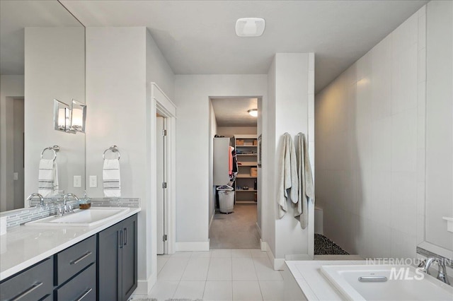 full bath featuring a spacious closet, vanity, tile patterned flooring, tiled shower, and baseboards