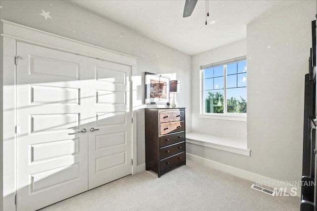 interior space with light carpet, baseboards, visible vents, and ceiling fan