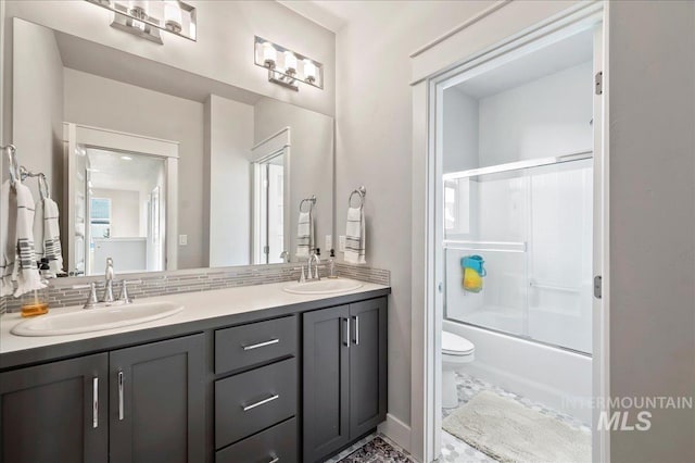 bathroom featuring enclosed tub / shower combo, double vanity, a sink, and toilet