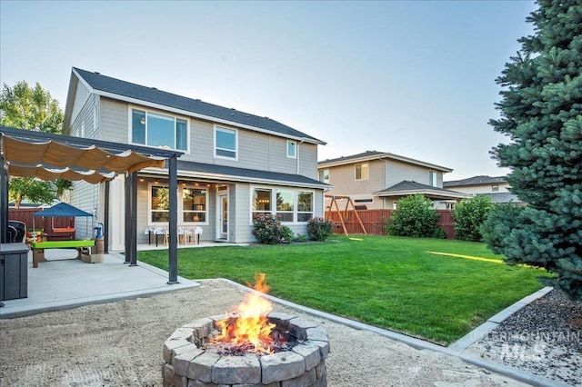 rear view of house featuring a lawn, fence, a fire pit, and a patio