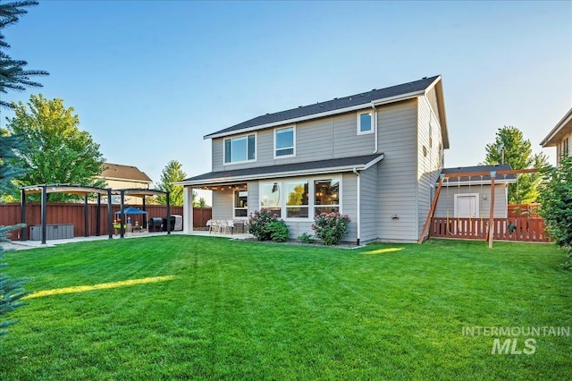 rear view of house featuring a yard, a patio area, fence, and a pergola