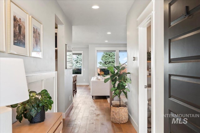 hallway featuring baseboards, light wood-type flooring, and recessed lighting