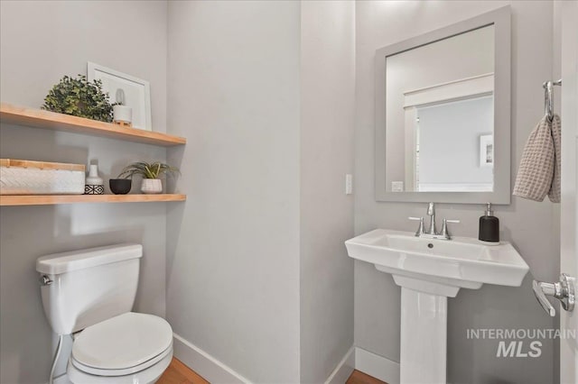 half bath featuring toilet and baseboards