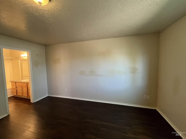 empty room with baseboards, dark wood-style flooring, and a textured ceiling
