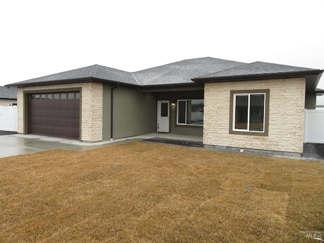 view of front of house featuring roof with shingles, concrete driveway, a front yard, a garage, and stone siding