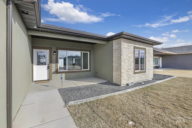 view of exterior entry with stone siding and stucco siding