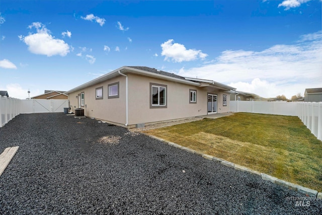 rear view of house with a patio, central AC unit, a fenced backyard, a yard, and stucco siding