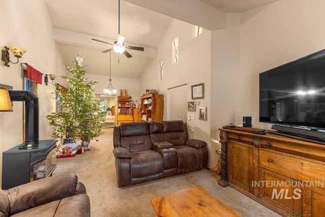 living room with ceiling fan, a wood stove, light colored carpet, high vaulted ceiling, and beam ceiling