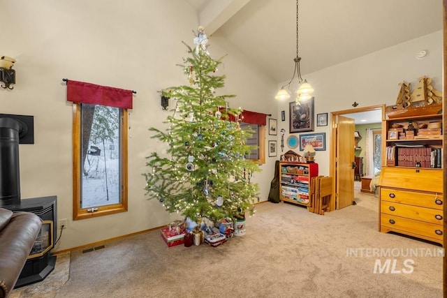 interior space with beam ceiling, a wood stove, carpet floors, and high vaulted ceiling