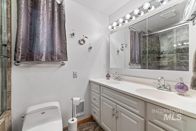 bathroom featuring a shower with shower door, vanity, and toilet