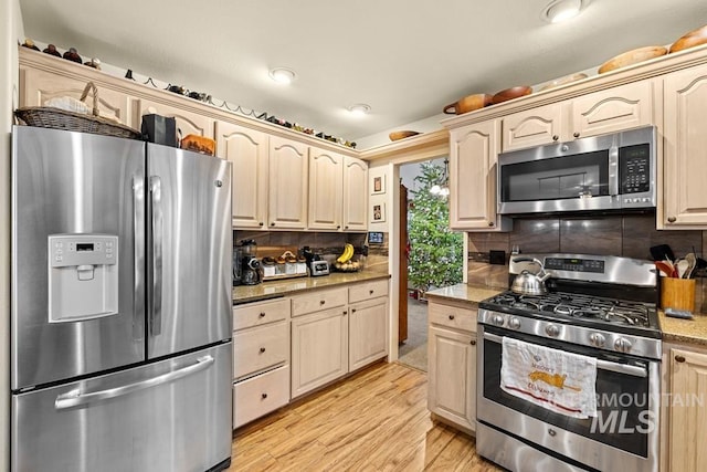 kitchen featuring appliances with stainless steel finishes, light hardwood / wood-style floors, and tasteful backsplash