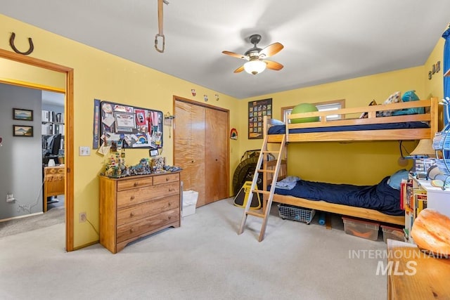 bedroom with light carpet, ceiling fan, and a closet