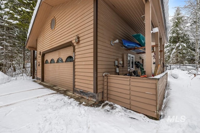 view of snow covered exterior featuring a garage