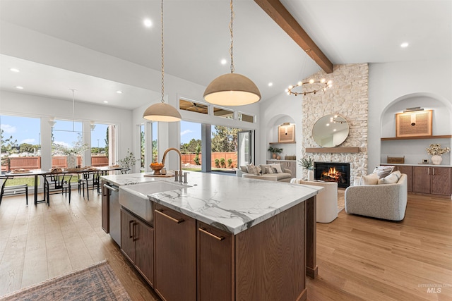 875 Creekwater, Eagle, ID 83616 - kitchen with a stone fireplace, beamed ceiling, light wood finished floors, a center island with sink, and recessed lighting
