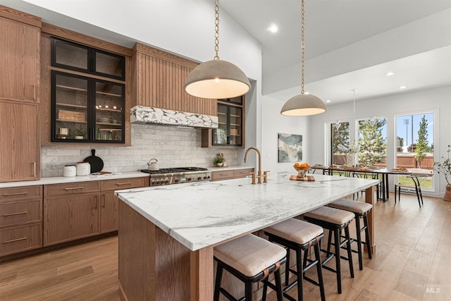 875 Creekwater, Eagle, ID 83616 - kitchen with backsplash, a breakfast bar, light wood-type flooring, light stone counters, and stove