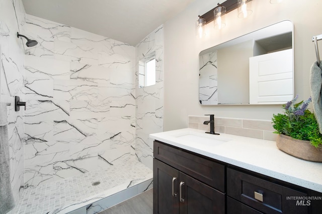 bathroom featuring tasteful backsplash, a marble finish shower, wood finished floors, and vanity