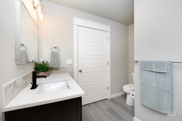 bathroom with toilet, wood finished floors, and vanity