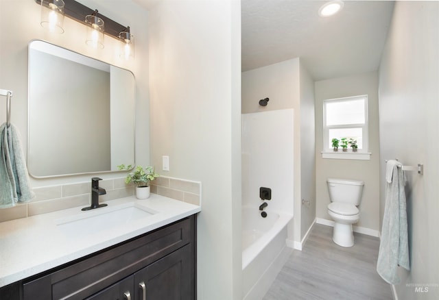 full bath featuring toilet, wood finished floors, vanity, bathing tub / shower combination, and baseboards