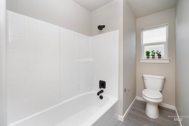 full bathroom with shower / bathing tub combination, wood finished floors, toilet, and baseboards