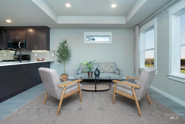 sitting room featuring a tray ceiling, light wood-type flooring, recessed lighting, and baseboards