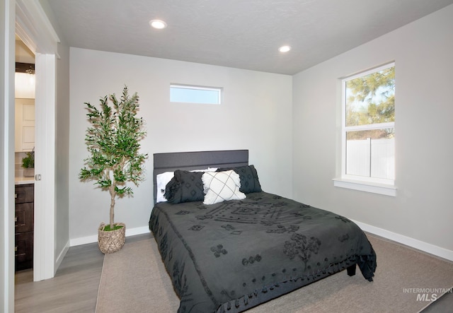 bedroom with light wood-type flooring, multiple windows, and baseboards