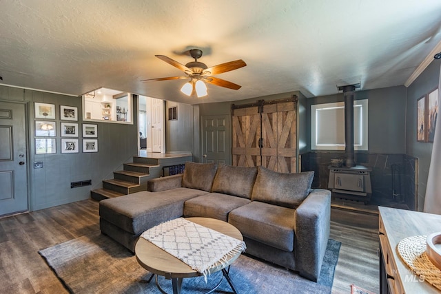 living room featuring a textured ceiling, a barn door, a wood stove, and dark wood-type flooring