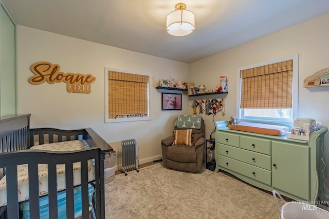 bedroom with a crib, light carpet, and radiator