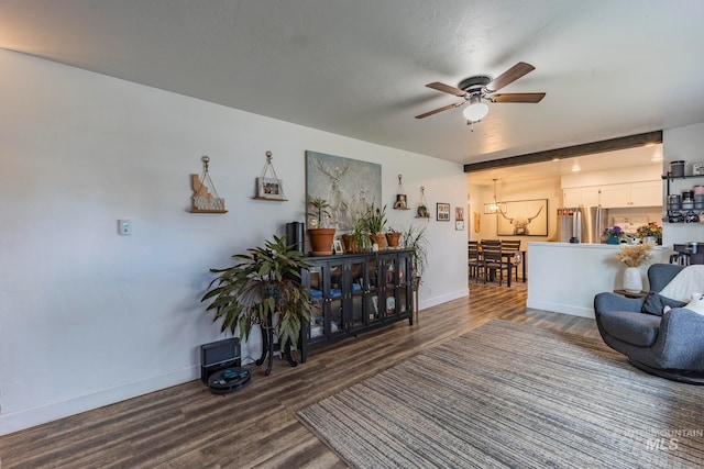 living room with dark hardwood / wood-style flooring and ceiling fan with notable chandelier