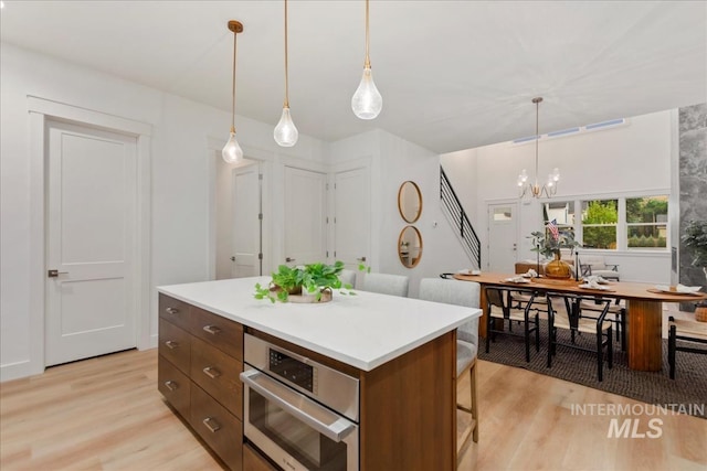 kitchen featuring a chandelier, light wood finished floors, a breakfast bar area, and stainless steel oven