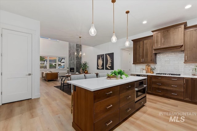 kitchen featuring light wood-style flooring, decorative backsplash, stainless steel appliances, and light countertops