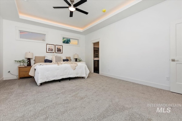 bedroom with baseboards, ceiling fan, a raised ceiling, and light colored carpet