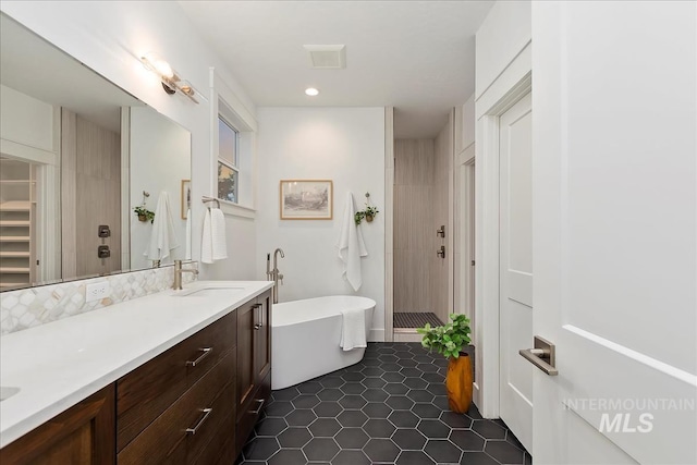 bathroom featuring a sink, visible vents, a freestanding bath, a tile shower, and double vanity