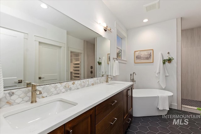 bathroom with double vanity, a freestanding tub, a stall shower, and a sink