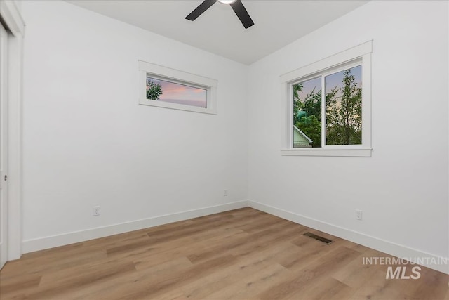 spare room with visible vents, light wood finished floors, a ceiling fan, and baseboards