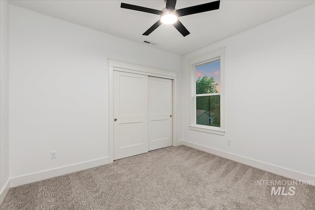 unfurnished bedroom with ceiling fan, light carpet, visible vents, baseboards, and a closet