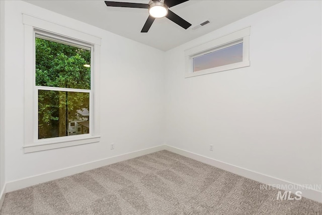 carpeted spare room with baseboards, visible vents, and ceiling fan