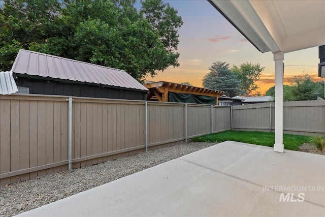 patio terrace at dusk featuring a fenced backyard