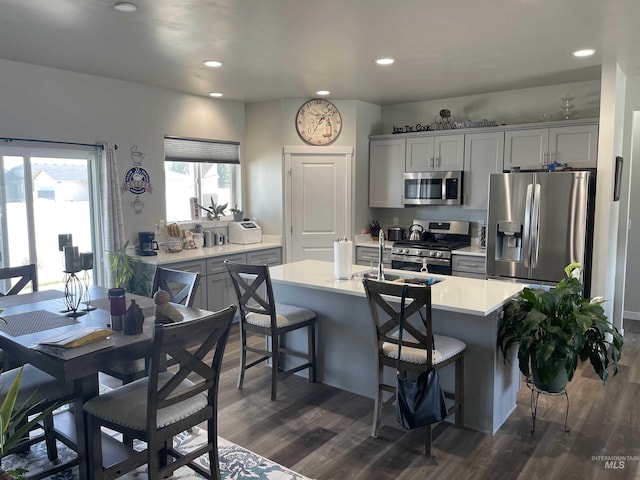 kitchen with a breakfast bar, recessed lighting, dark wood-style flooring, stainless steel appliances, and light countertops