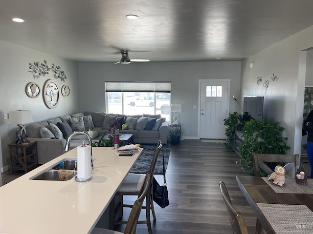 interior space with a sink, a kitchen breakfast bar, open floor plan, dark wood-style floors, and ceiling fan