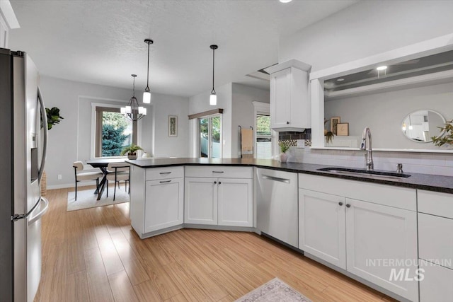 kitchen featuring a healthy amount of sunlight, stainless steel appliances, white cabinetry, and a sink