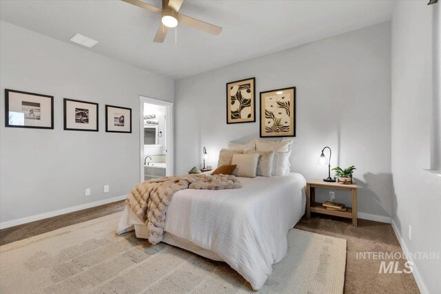 bedroom with ceiling fan, visible vents, ensuite bathroom, baseboards, and light carpet